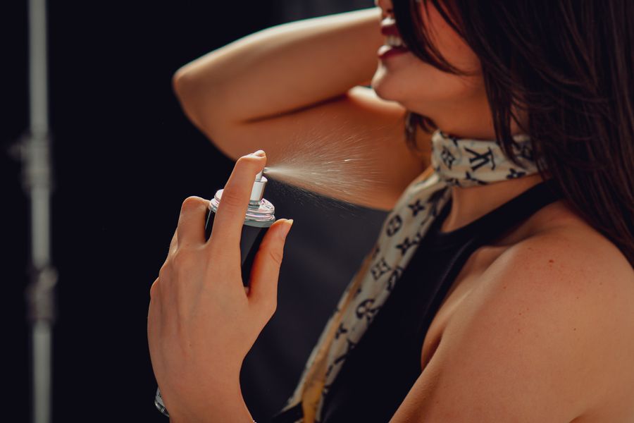 Aplicación de perfume en cuello femenino