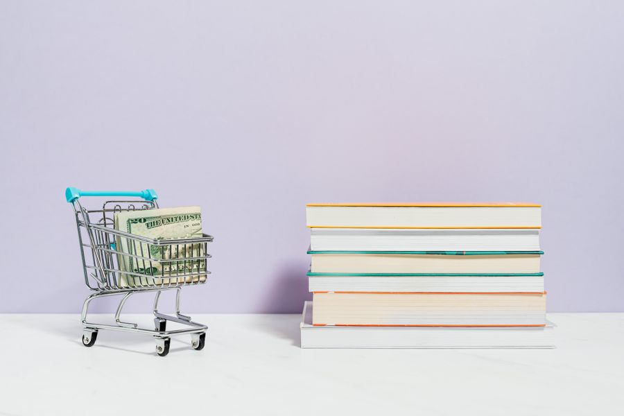 Carro de compras con billetes y libros de finanzas personales
